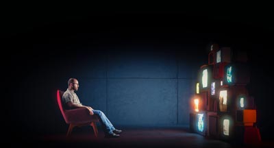 גבר מול הרבה מסכים בחדר חשוך