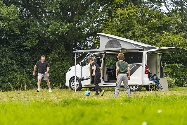 ילדים משחקים כדורגל עם אביהם