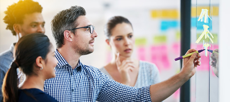 מנטור-של-המנטורים-סופר-מנטור-לייצר-השפעה-ולהרוויח-ממנה בתמונה מנטור מראה לסטודנטים משהו על הלוח